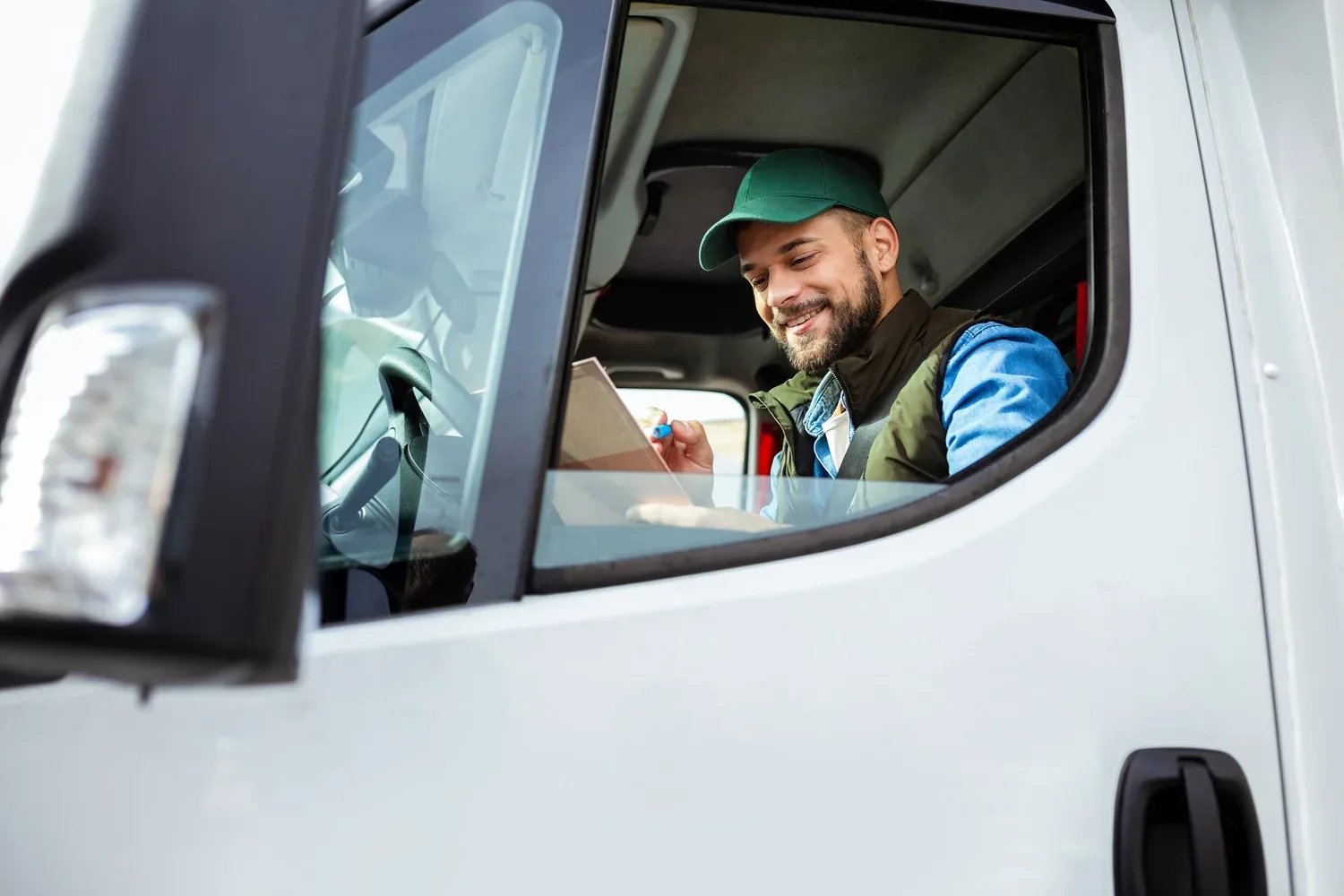 A driver at the wheel of his truck, checking paperwork